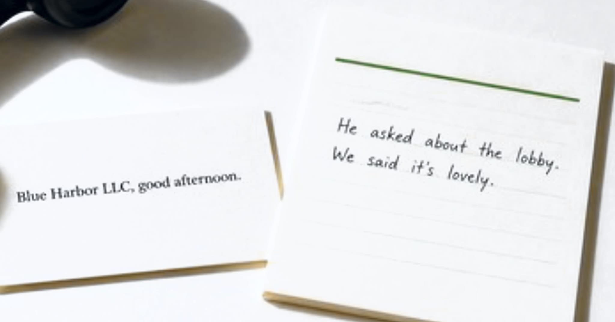 A black handset off its cradle, a card reading Blue Harbor LLC, good afternoon, and a message slip: He asked about the lobby. We said it’s lovely.